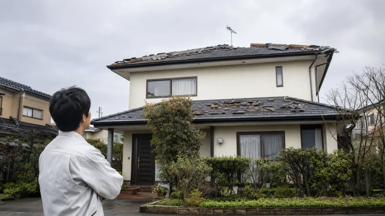 台風後の日本の戸建て住宅と屋根を地上から確認する施主
