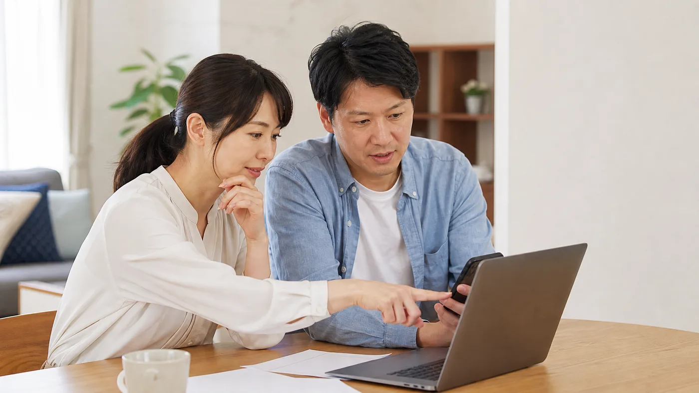 給湯器交換の見積もり条件をパソコンとスマートフォンで比べる日本人夫婦のイメージ